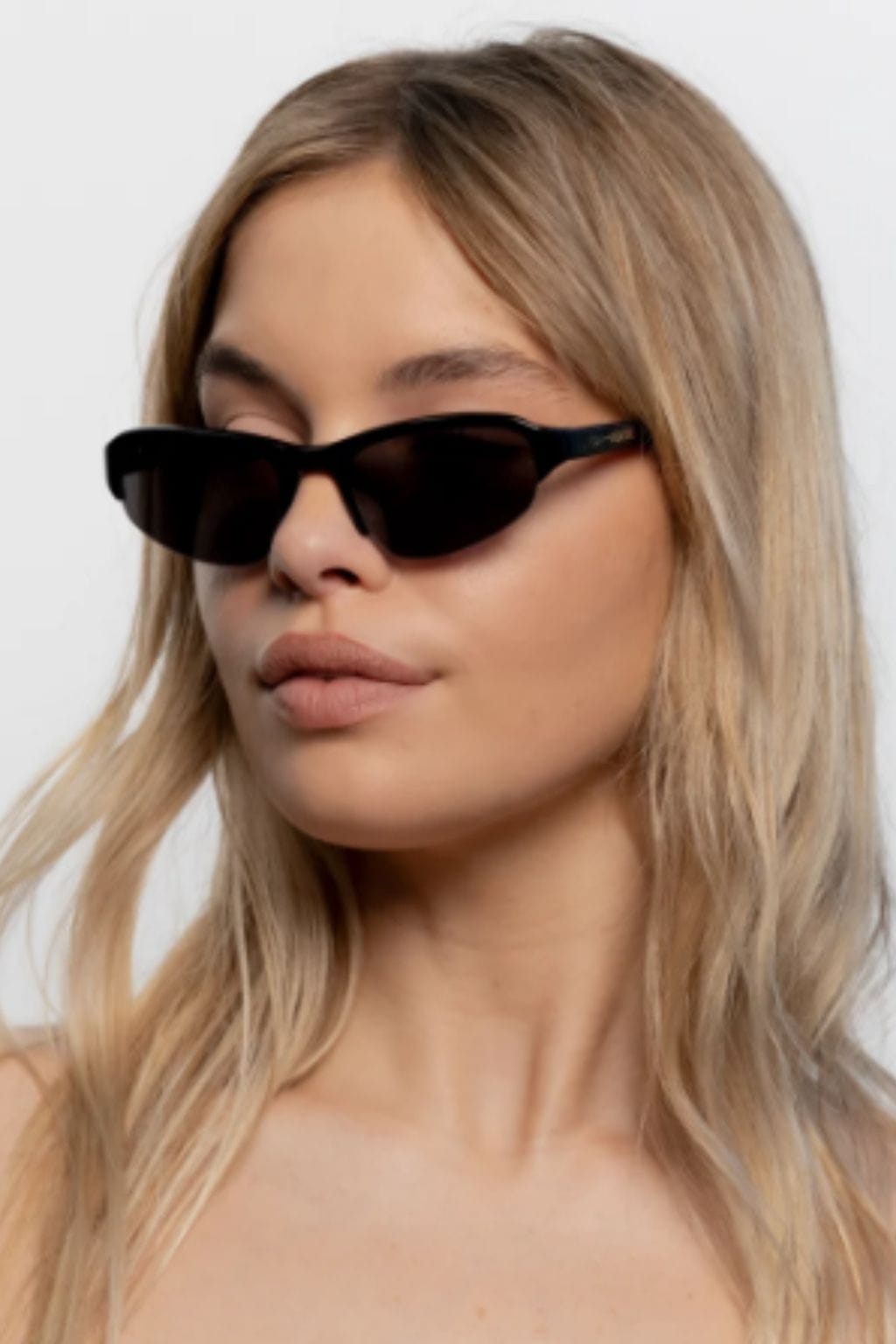 Black oval sunglasses with dark lenses worn by a person with long blonde hair.