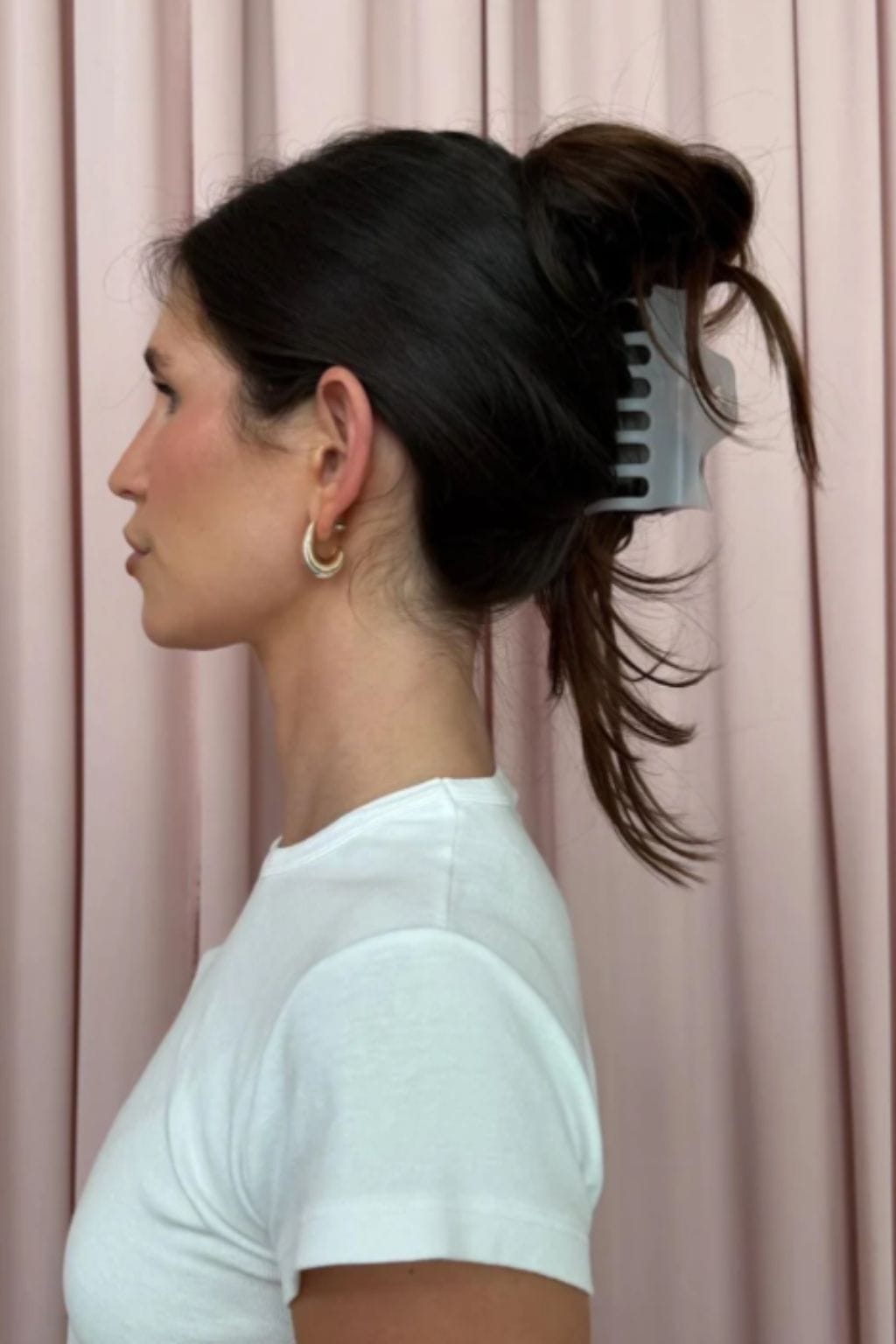 Grey smoke claw clip holding dark hair in an updo on a person in profile view.