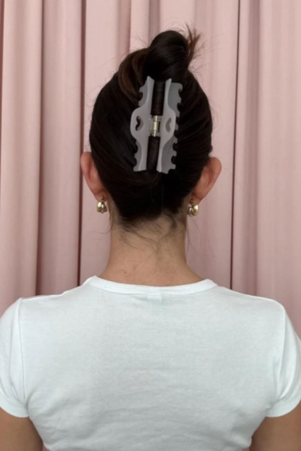 Lilac smoke-colored hair clip with wavy edges worn in an updo hairstyle.