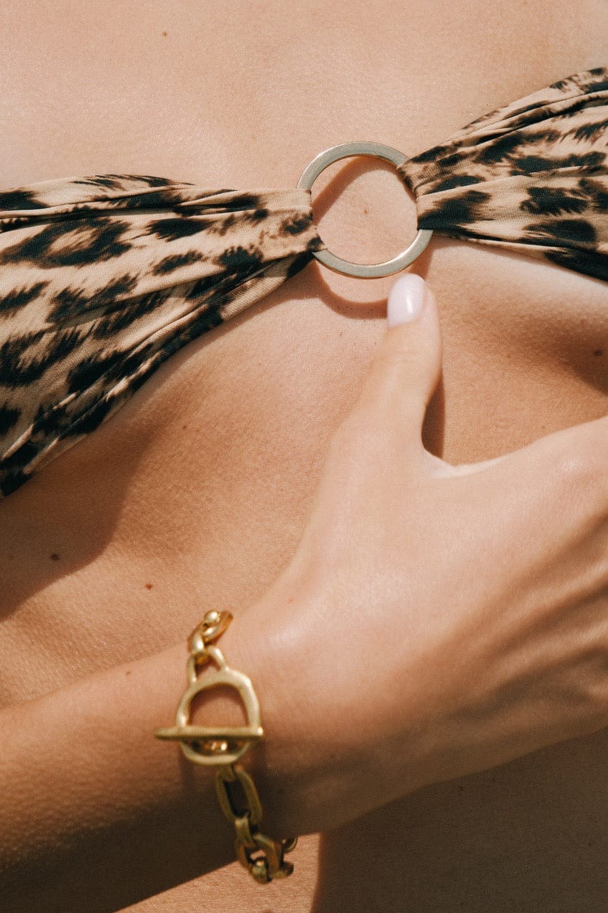 Gold-toned chain bracelet with toggle clasp, worn on wrist with patterned scarf.