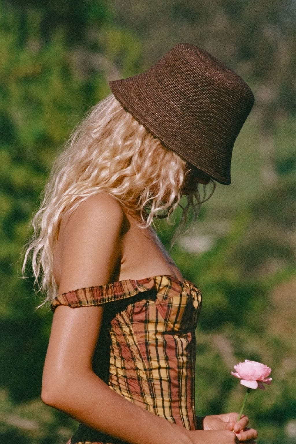 Brown woven bucket hat with textured crown and downturned brim.