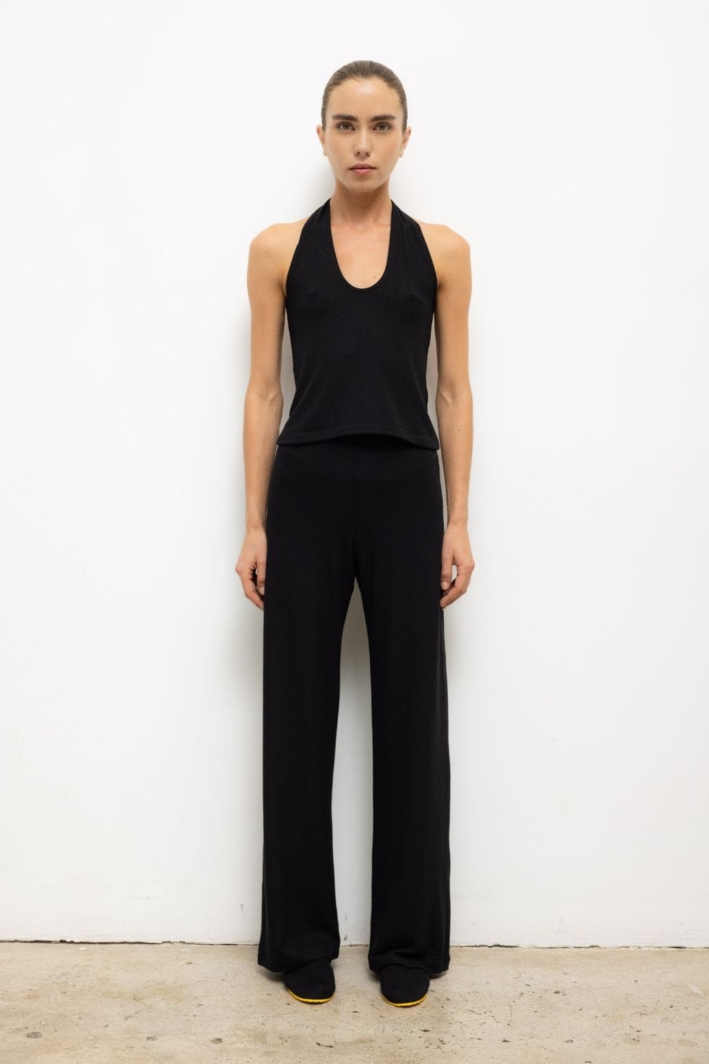 Woman wearing black halter neck top and black wide-leg pants.