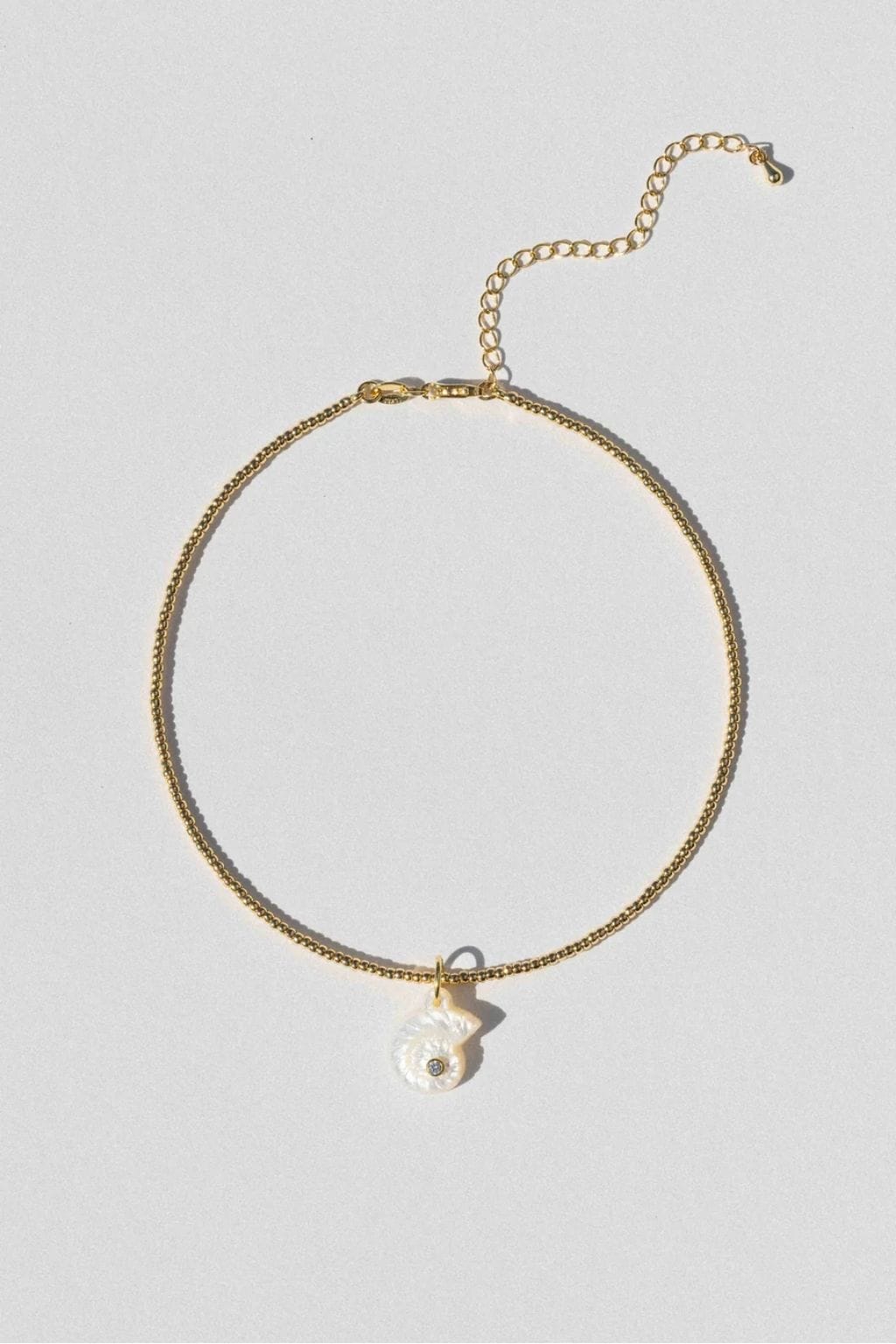 Gold-toned choker necklace with textured chain and white shell pendant charm.