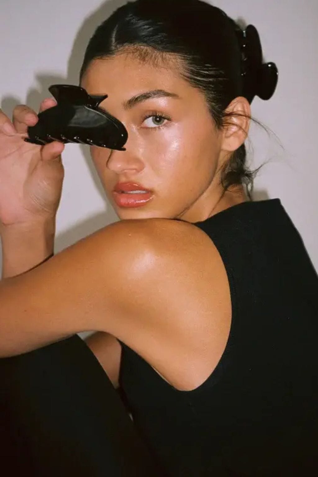 Black claw-shaped hair clip shown held in hand and worn in hair.