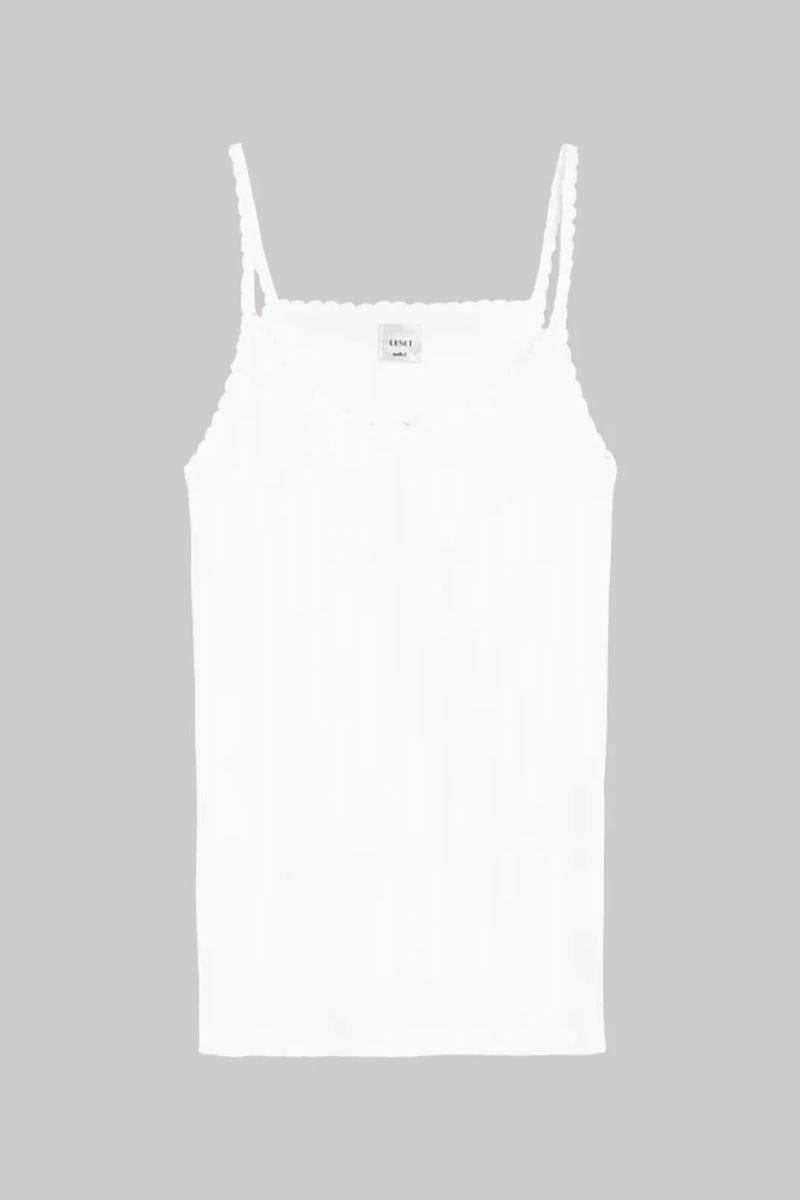 White pointelle tank top with thin straps and scalloped neckline and armholes.
