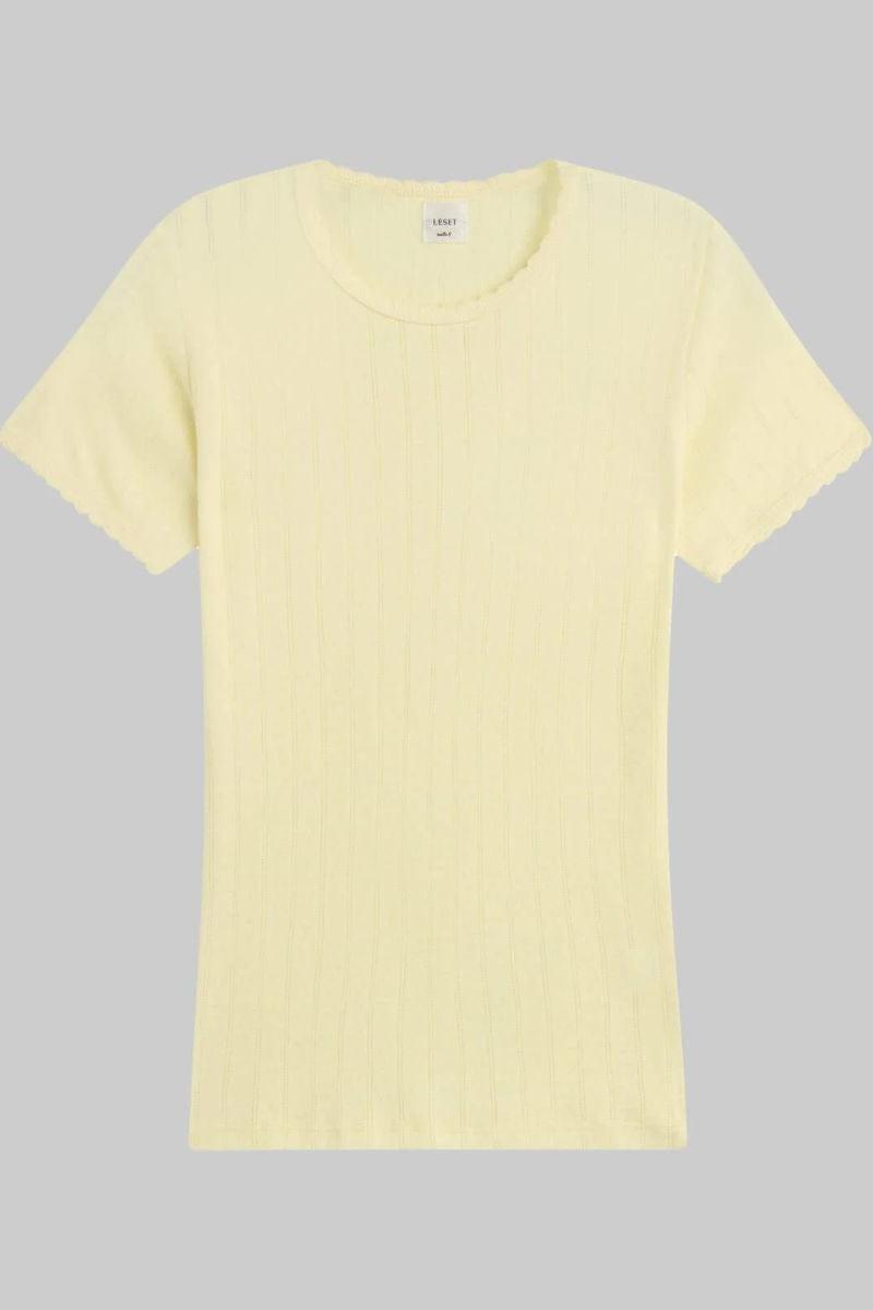 Pale yellow pointelle knit t-shirt with short sleeves and crew neckline, displayed on gray background.