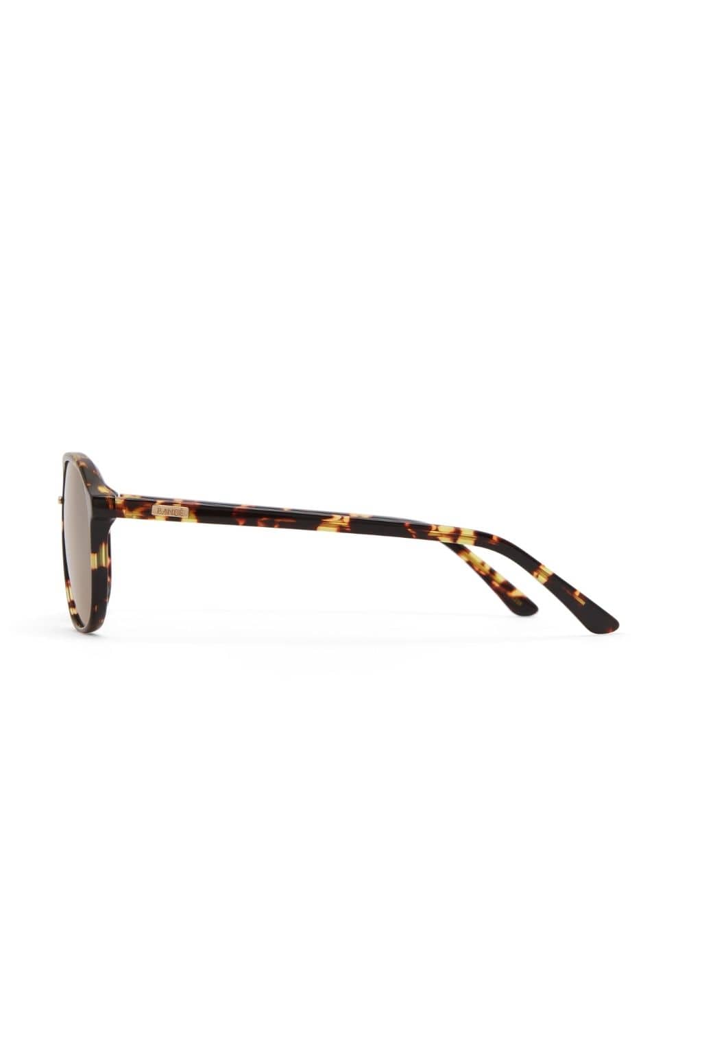 Amber tortoise round sunglasses with dark lenses and patterned yellow and brown acetate frames.