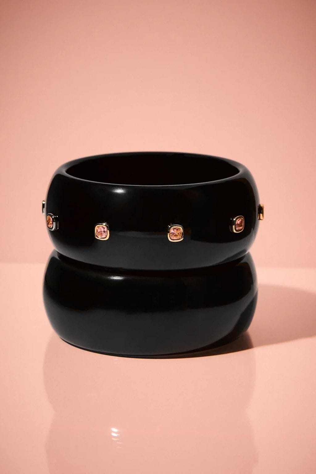 Black lucite cuff bracelet with rose gold-tone square gemstone accents around the band.