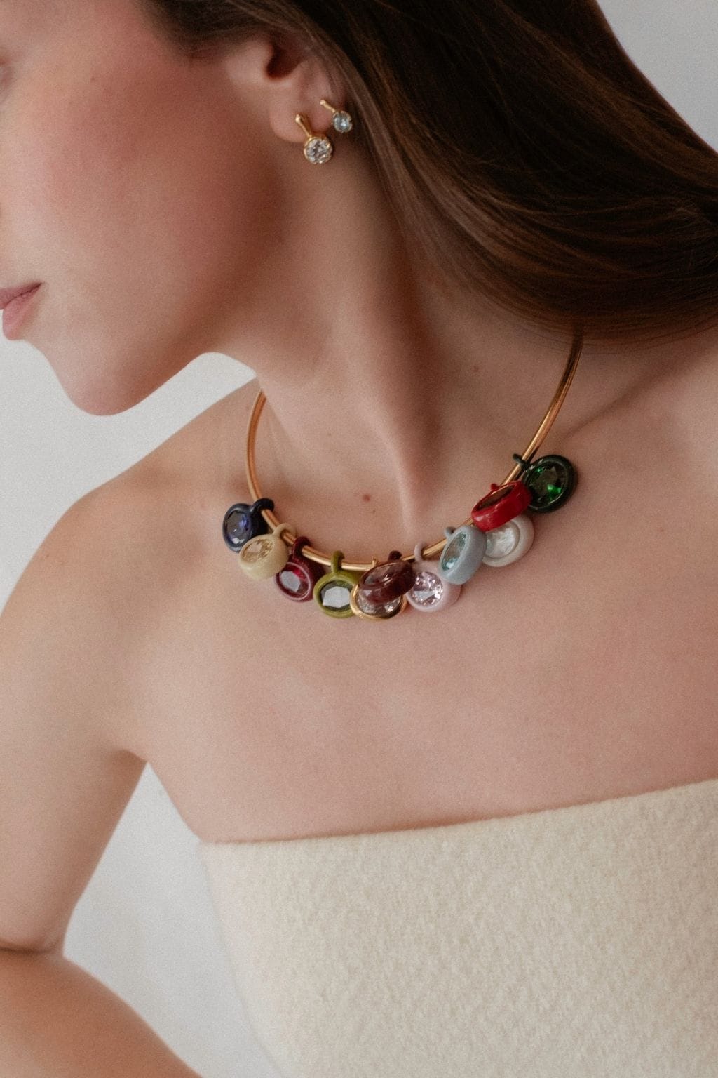 Gold-toned necklace with multiple colorful gemstone charms and matching diamond stud earrings worn on model.