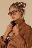 Brown scarf with cream polka dots, tied around the head as a headwrap.