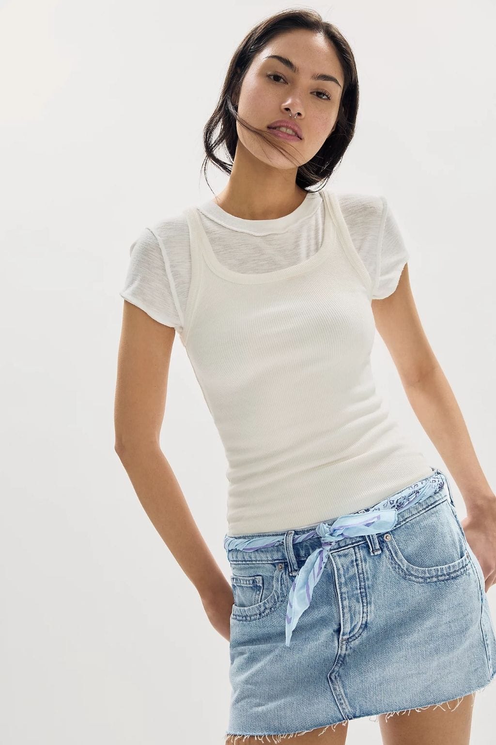 Woman wearing cream ribbed short-sleeve shirt and light blue denim mini skirt with tie-front waistband and distressed hem.
