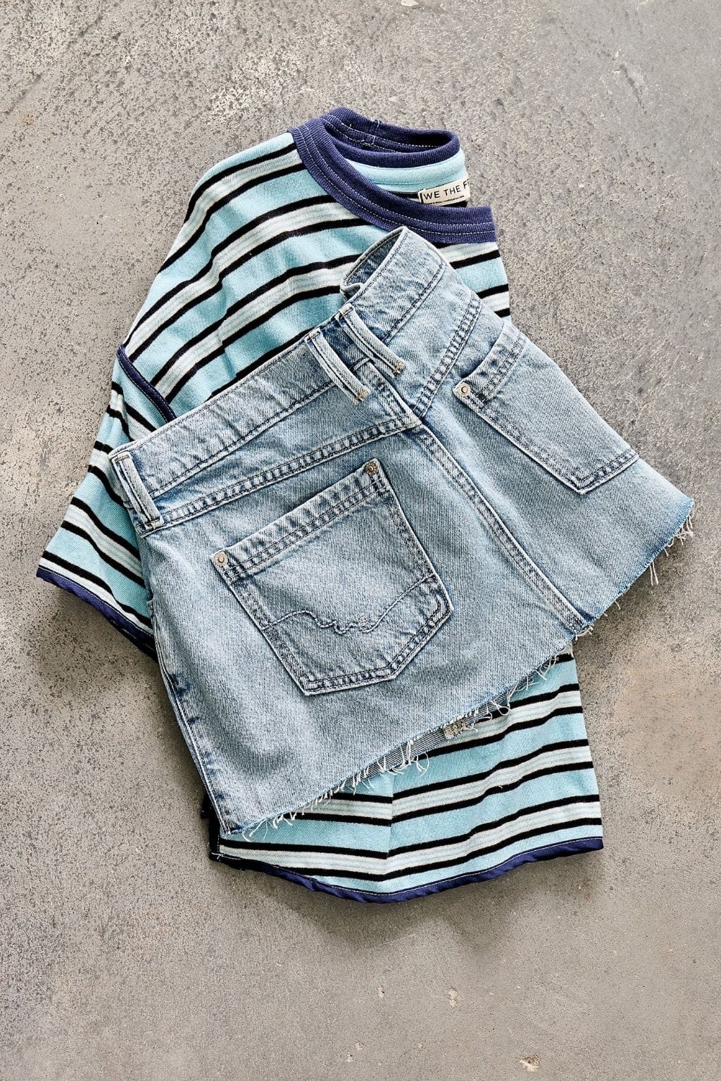 Light blue denim mini skirt with frayed edges displayed with striped knit sweater in light blue, navy, and white.