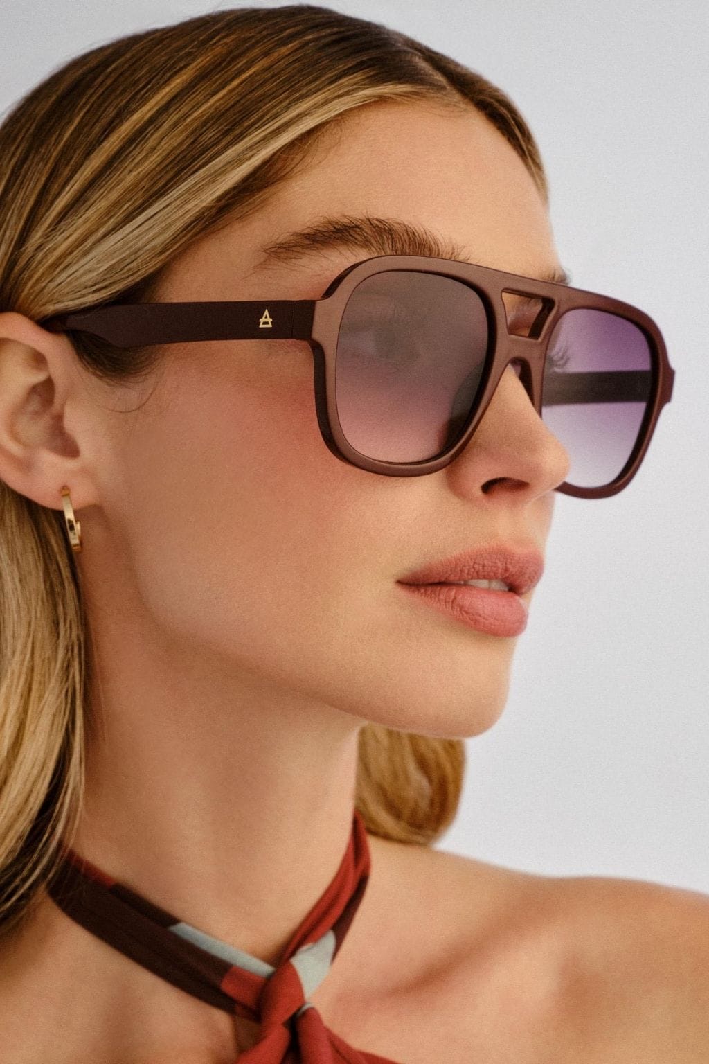 Burgundy square sunglasses with gradient purple lenses worn by a person in profile.