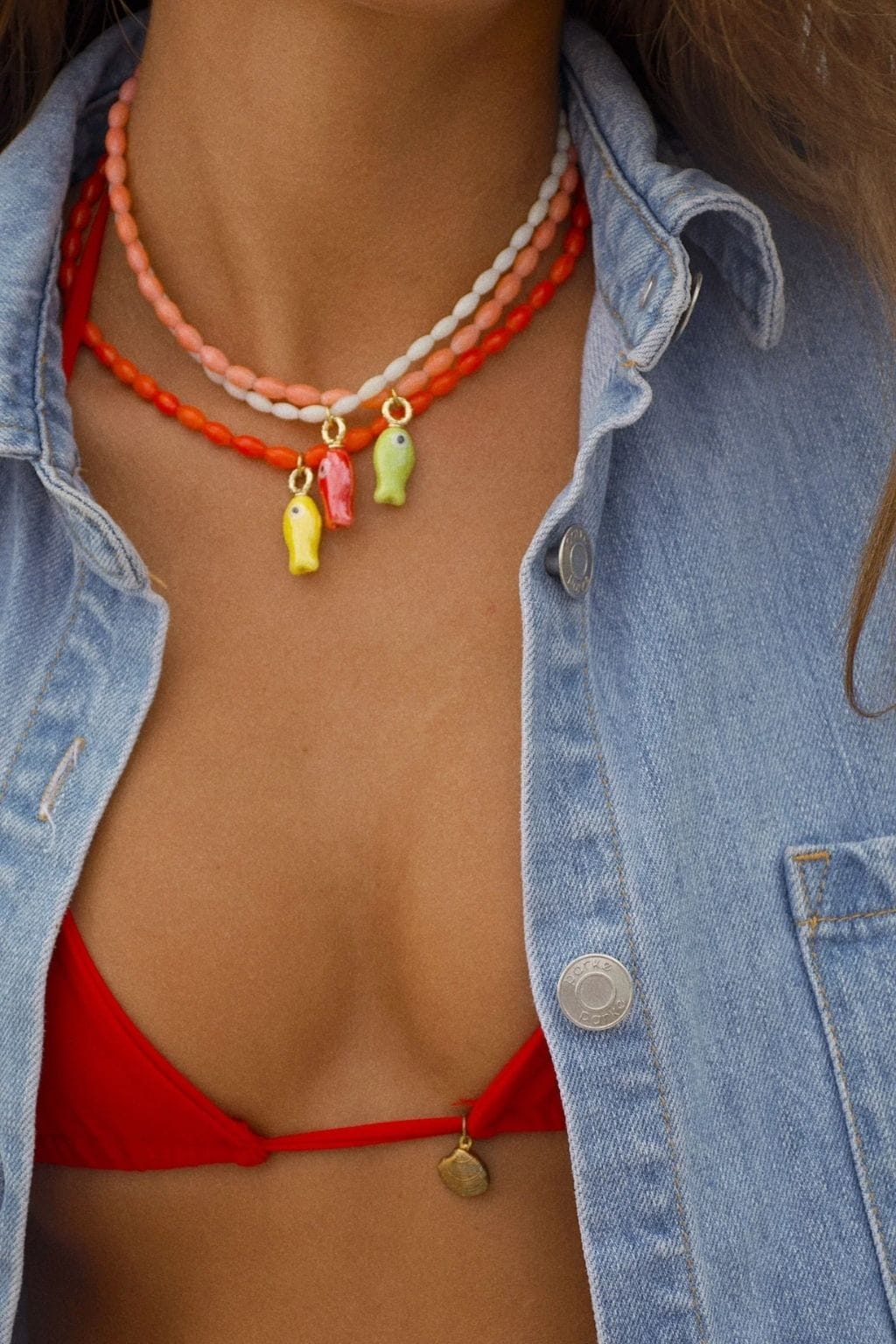 Beaded necklace with red, orange, and white beads featuring three dangling fish charms in yellow, red, and green.
