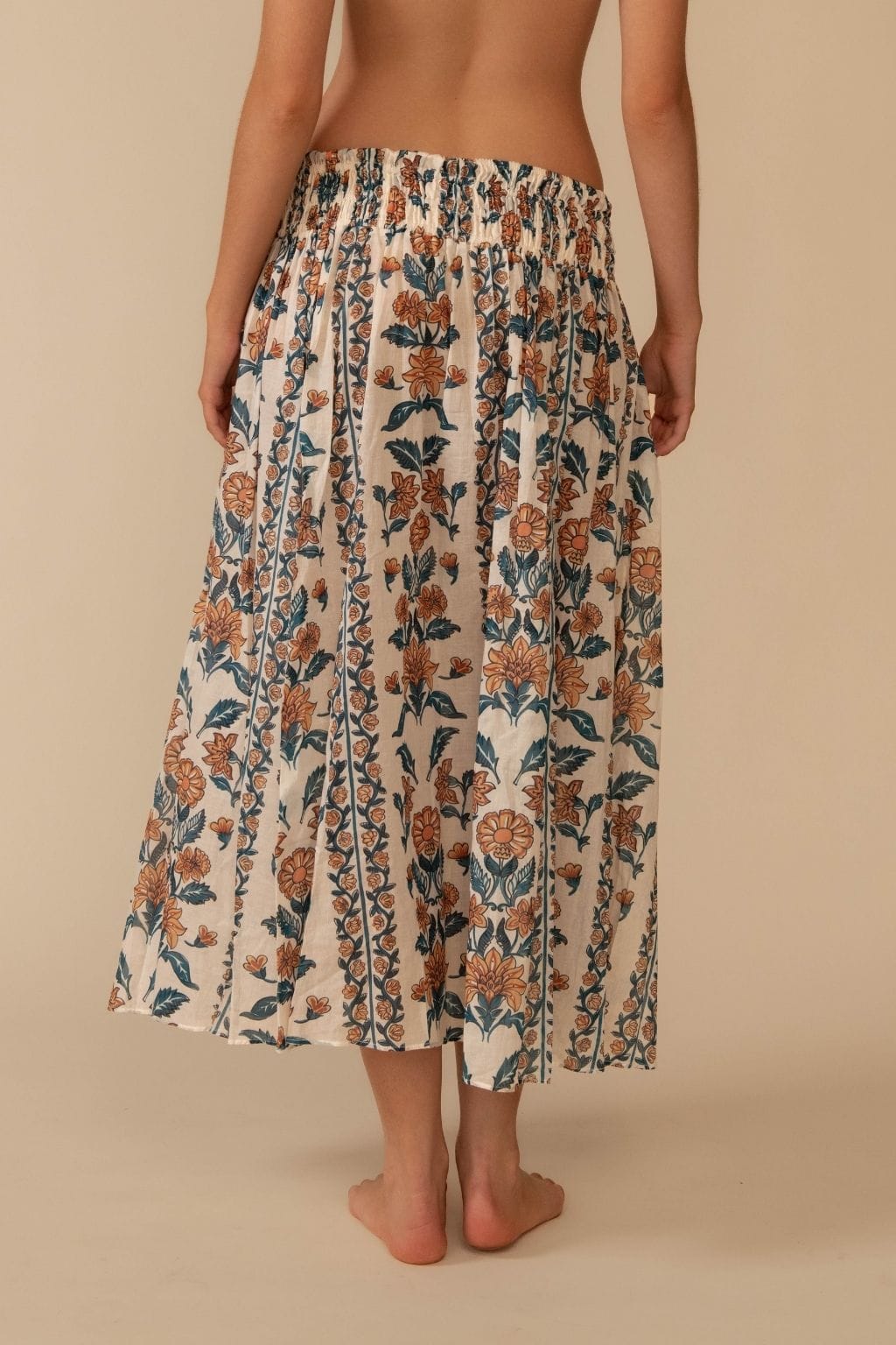 Cream midi skirt with orange and teal floral print, elastic waistband, and flowing A-line silhouette.