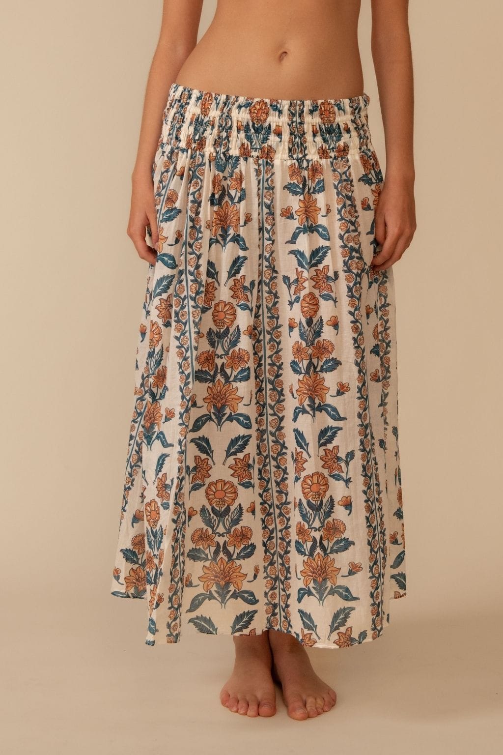 Cream midi skirt with orange and navy floral print, elasticated waistband, and flowing A-line silhouette.