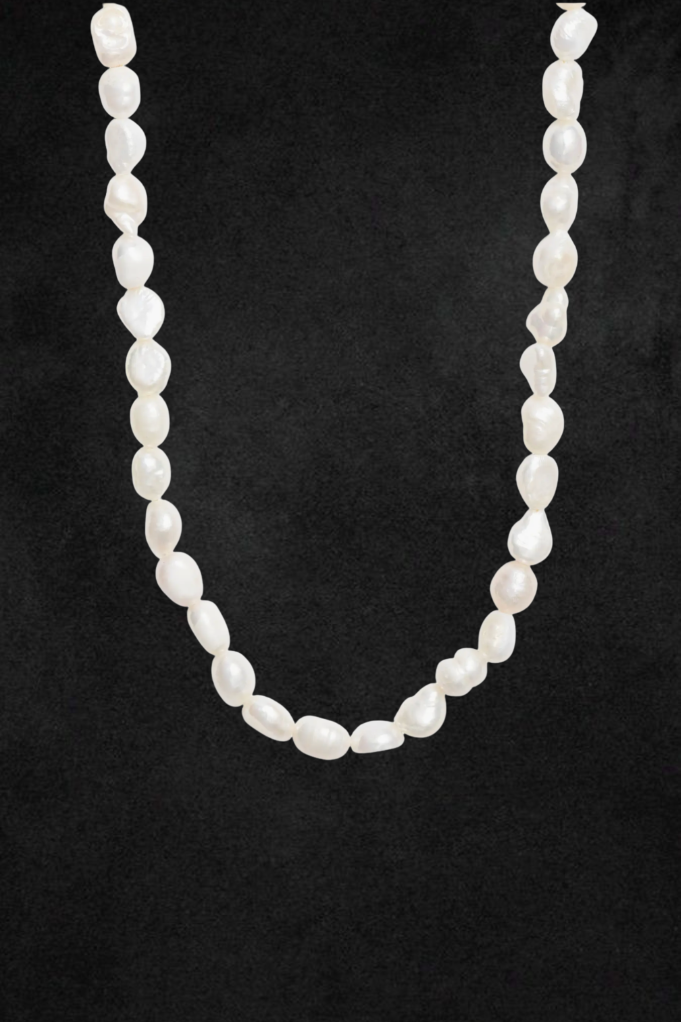 White pearl necklace with oval-shaped beads strung in a continuous strand against a dark background.