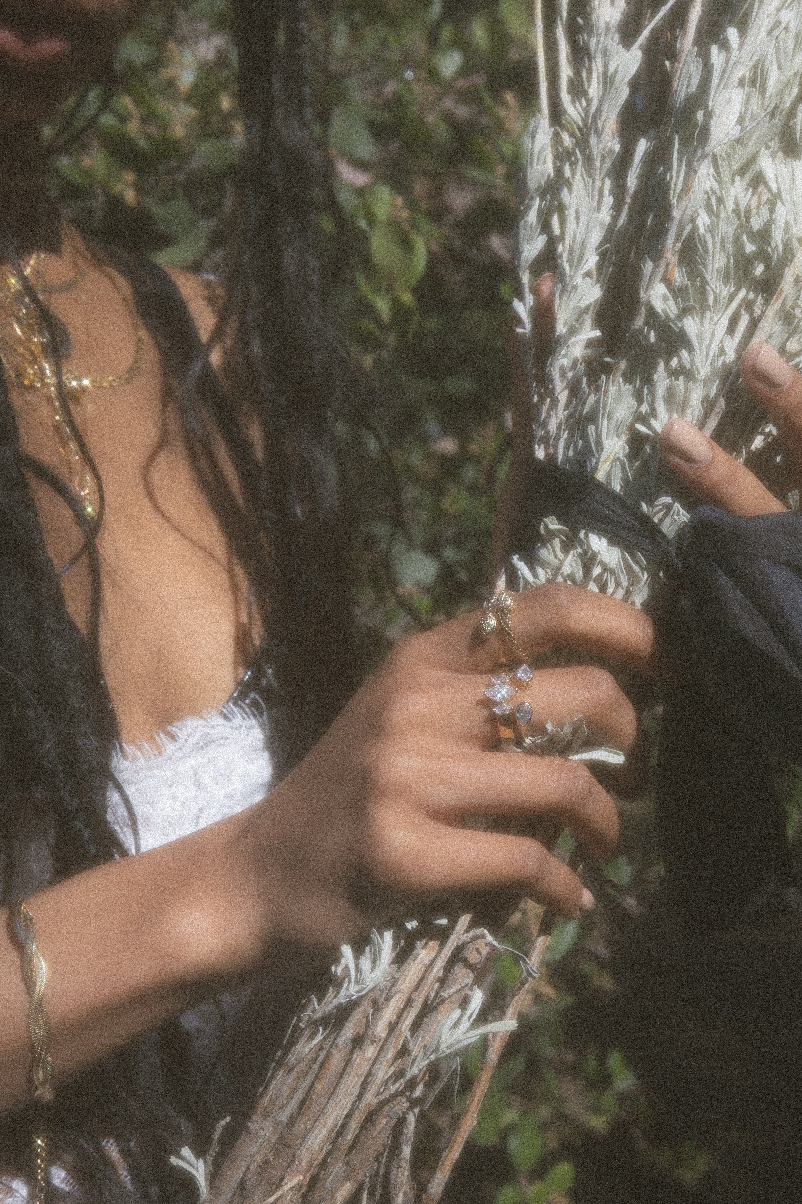 Silver-toned ring with square cubic zirconia stone worn on hand against textured bark background.