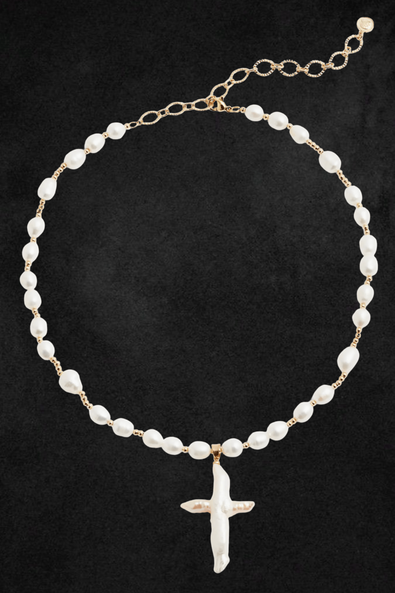 Gold-tone chain necklace with white pearl beads and white cross pendant on black background.