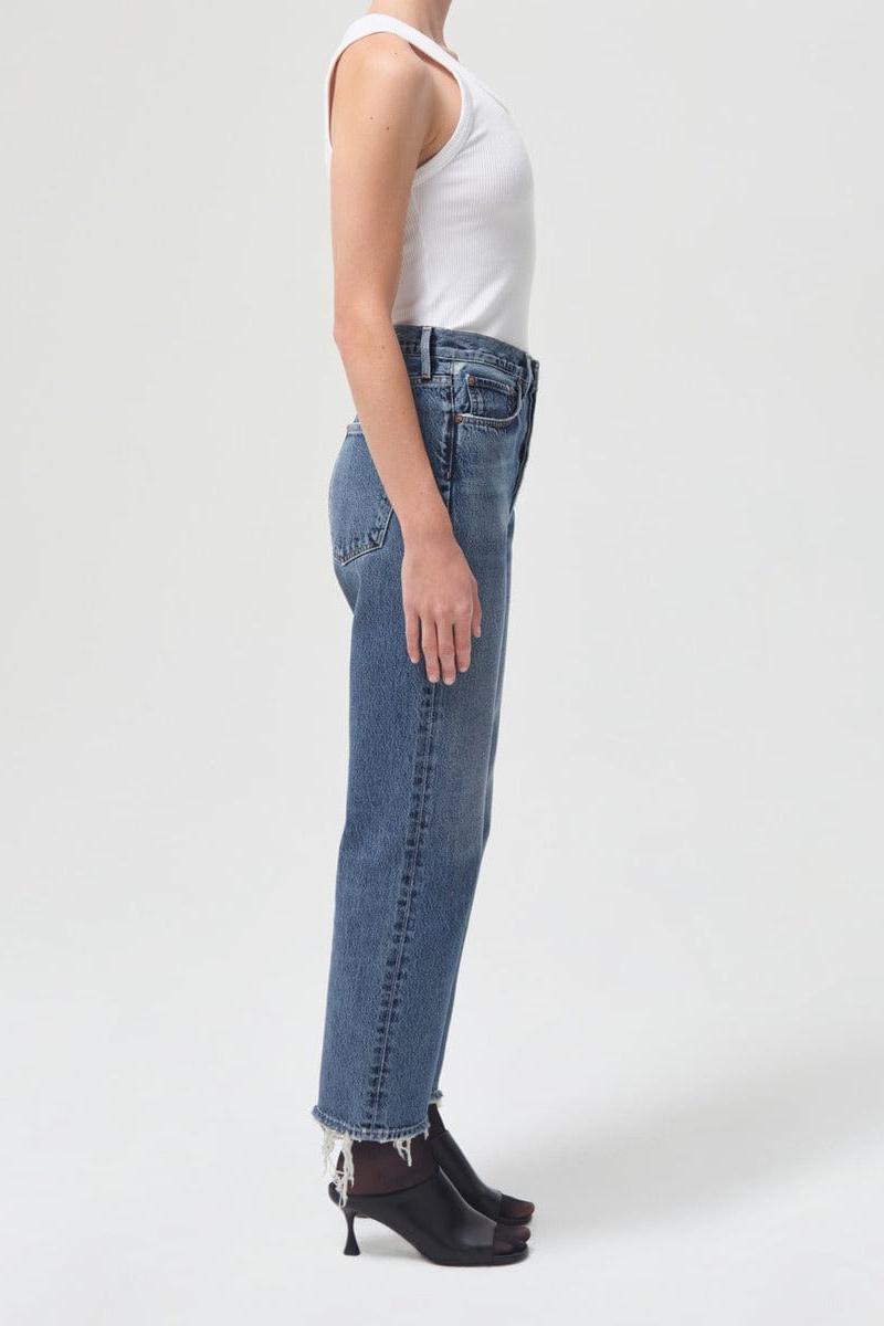 White ribbed tank top paired with medium-wash blue jeans and black platform heels, shown on model from side angle.